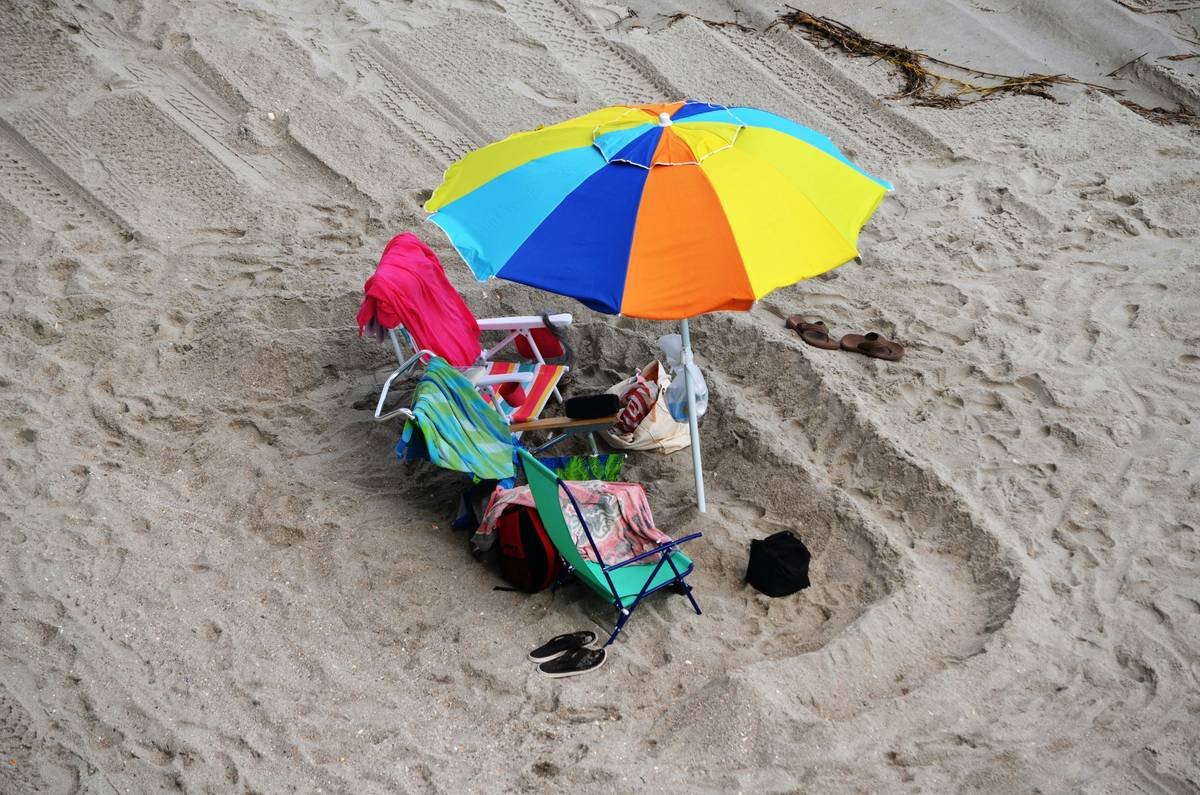 Comparison chart showing weight vs. stability for common beach umbrella bases: screw-in anchor (15 lbs, low stability), sand-filled bag (30 lbs, medium), dual-chamber steel base (50 lbs, high)