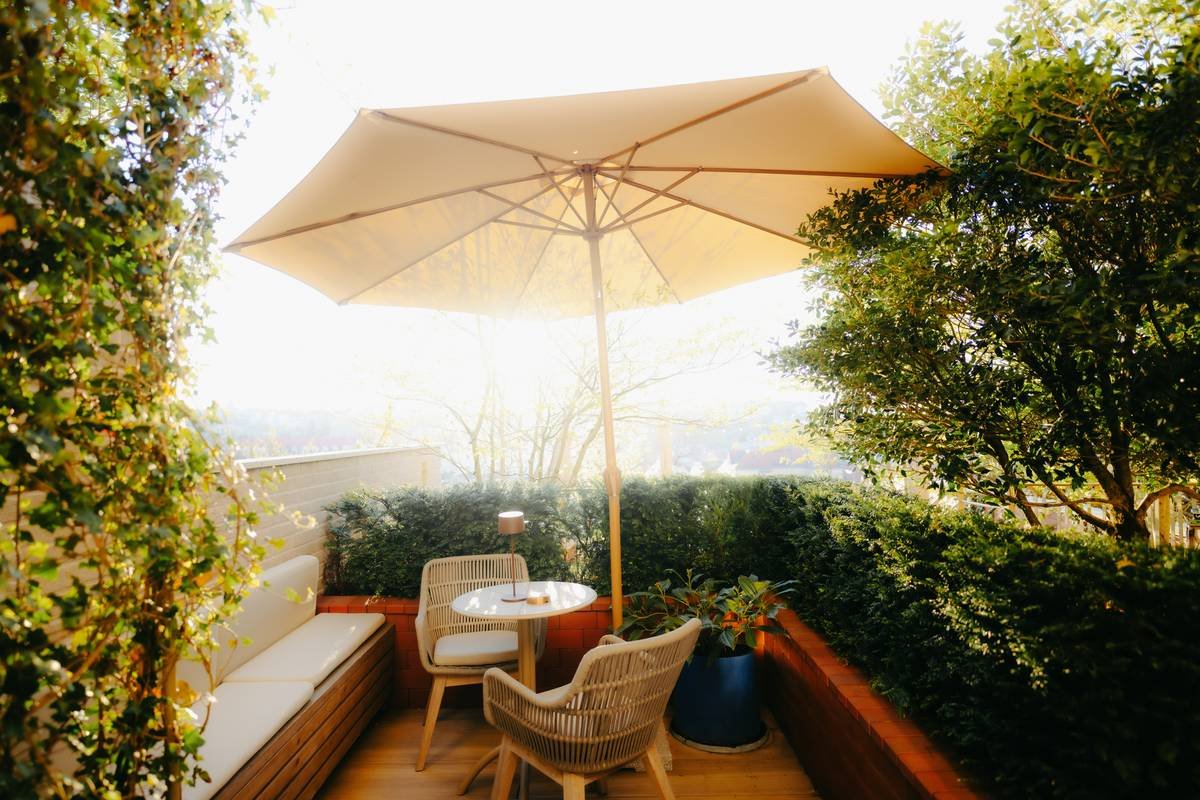 Side-by-side comparison: low-quality vs high-quality outdoor furniture with umbrella showing material durability, base stability, and fabric UV resistance