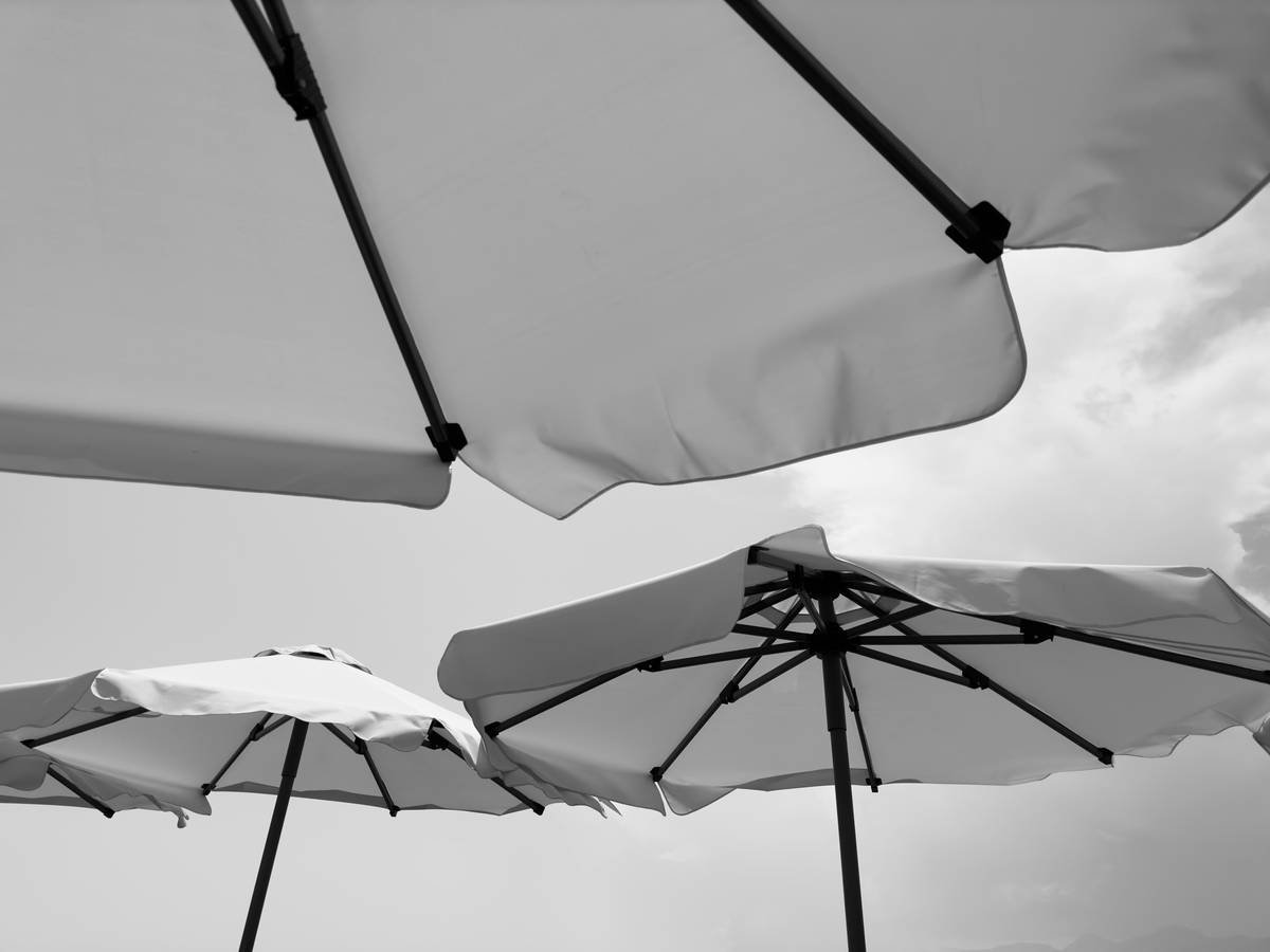 Infographic showing wind speed vs. uplift force on beach umbrellas: 15 mph = 20 lbs force, 25 mph = 55 lbs force