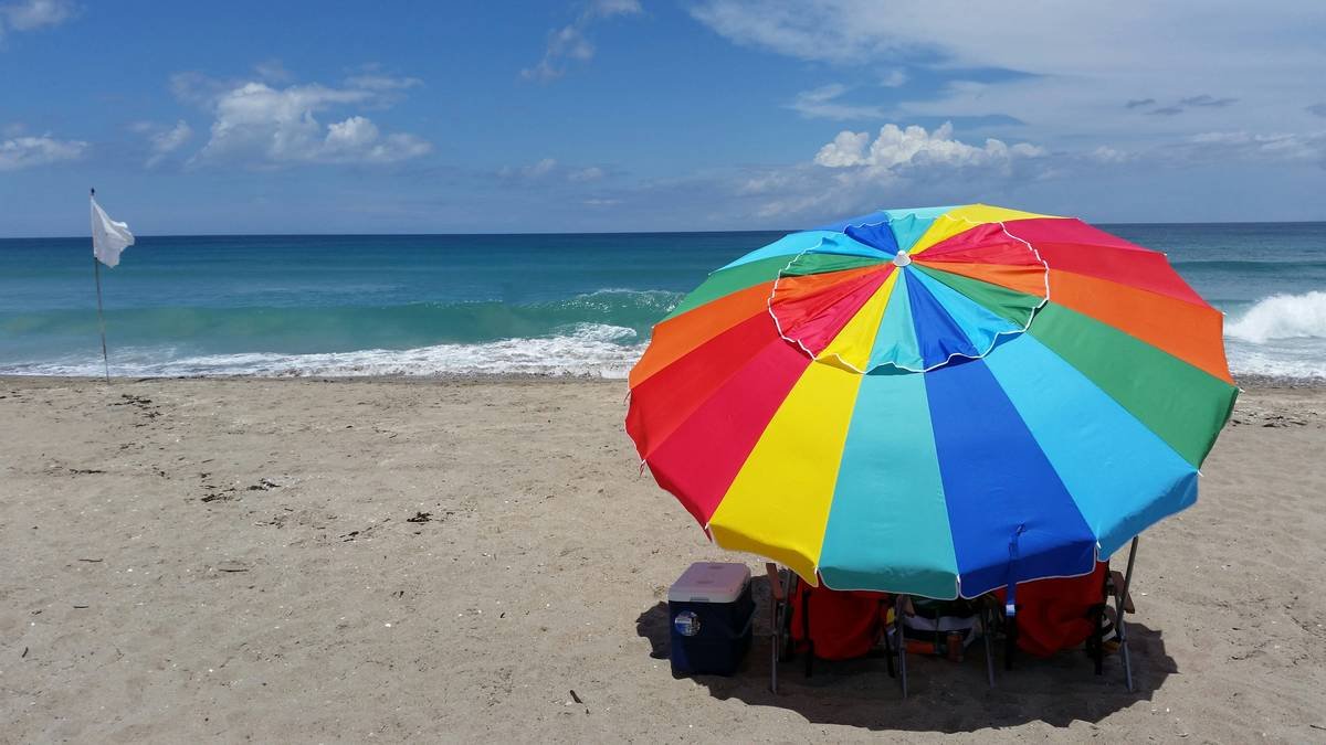 Side-by-side infographic showing UV protection levels: regular fabric (UPF 5) vs. certified UPF 50+ beach umbrella fabric blocking 98% of UV rays