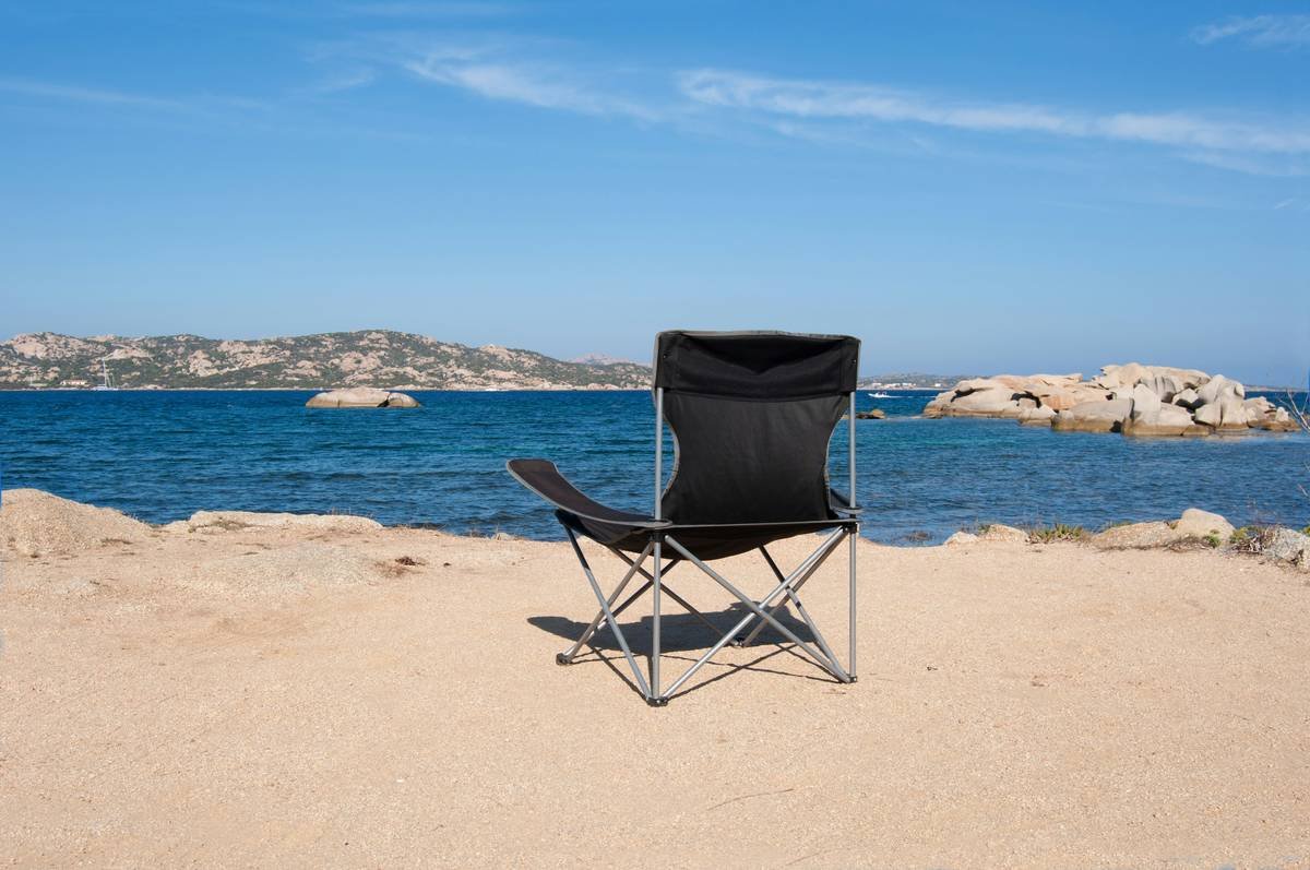 Compact foldable beach chairs with umbrella attached on sandy shore