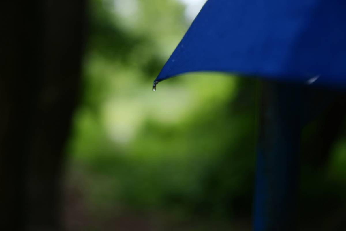 Person rinsing a patio umbrella cover during how to clean patio umbrella covers process